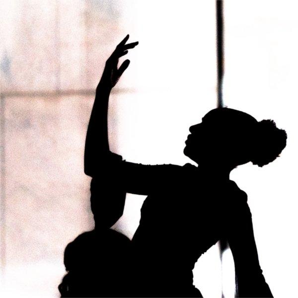 A dancer is silhouetted with the hand in the air.