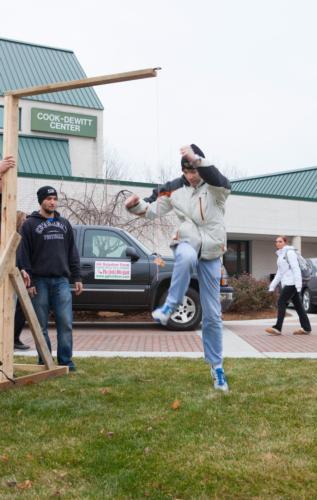 A student tries the high-kick game. Eric DeVries, a junior, is standing nearby.