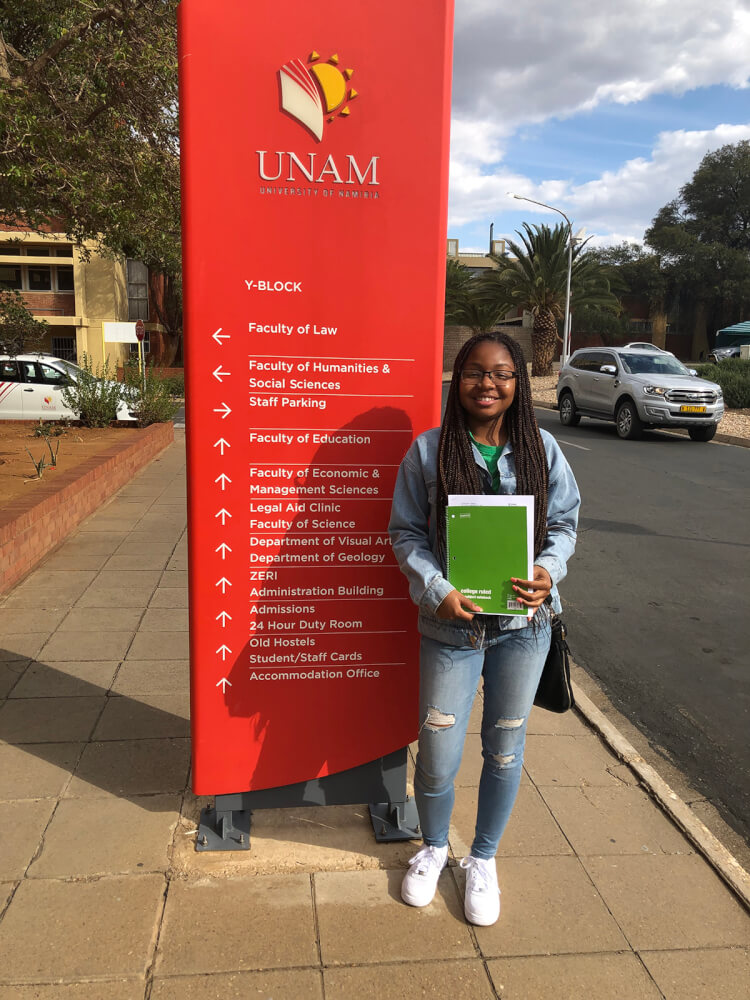 student standing in front of sign at African university