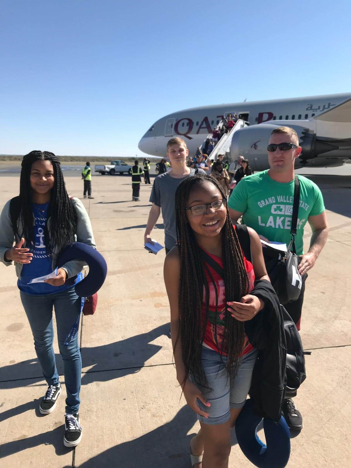 students stepping off plane on runway