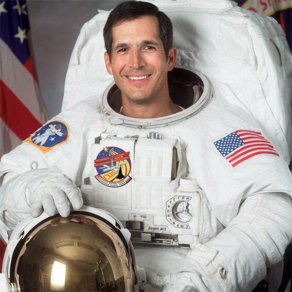 A person wearing an astronaut uniform smiles.