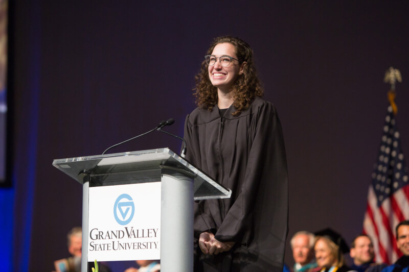 woman standing on stage in graduation gown