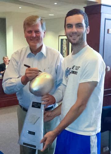 President Thomas J. Haas signs a fantasy football league trophy for Kyle Partlo, a computer engineering major.