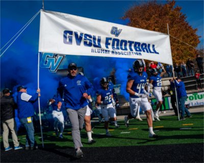 The Grand Valley football team and head coach Scott Wooster run onto the field at Lubbers Stadium.