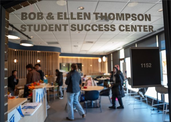 students walk in room, name on glass: Bob and Ellen Thompson Student Success Center