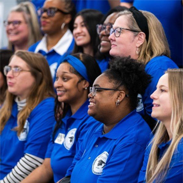 group photo of two rows of people in blue shirts