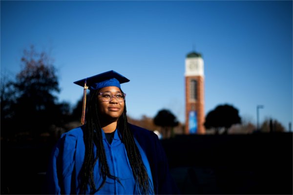 A person wearing blue academic garb looks off to the side. The carillon is in the background.