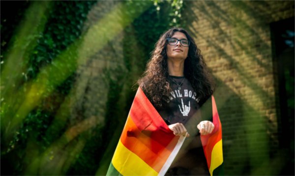  A person drapes themselves in a pride flag for a portrait.
