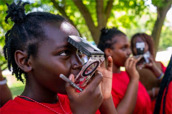 A young child puts their face into a compass during camp. 