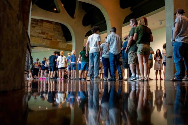  A long line of people are reflected into a shiny floor. 
