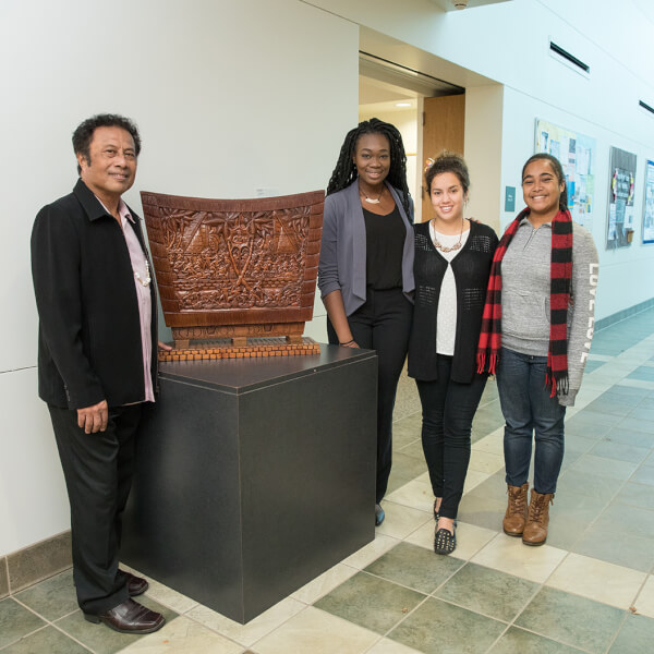 four people by wooden artwork