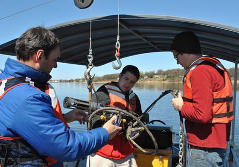 From left, Observatory Manager Scott Kendall, graduate student Leon Gereaux, and Research Technician Tom Holcomb adjust settings as they lower a string of sensors into the lake.