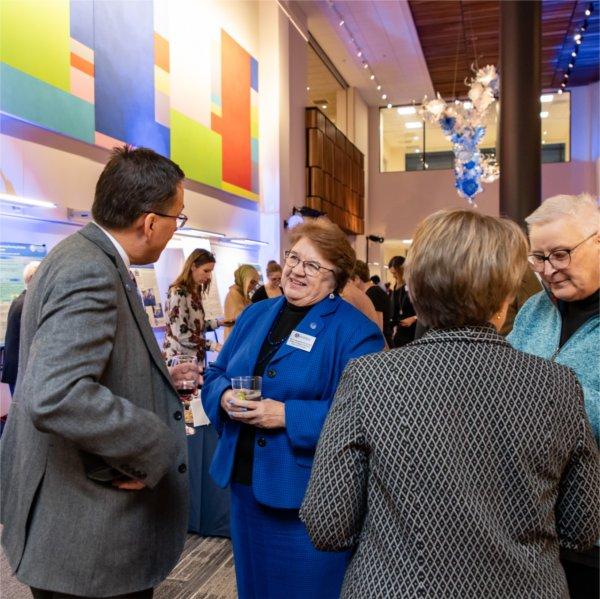 reception with four people standing talking with colorful artwork in the background