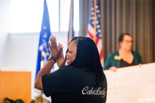 Corine Rose with Corine's Cakes & Catering, LLC reacts to receiving a check for $11,800 from the Hub Direct Grant Program at the Muskegon Innovation Hub August 15. 