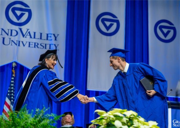 President Mantella shakes a student's hand as they walk across the stage at Commencement.