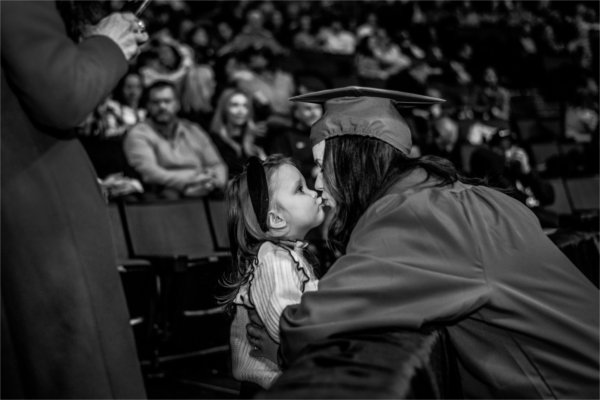 A graduate kisses a child after commencement.