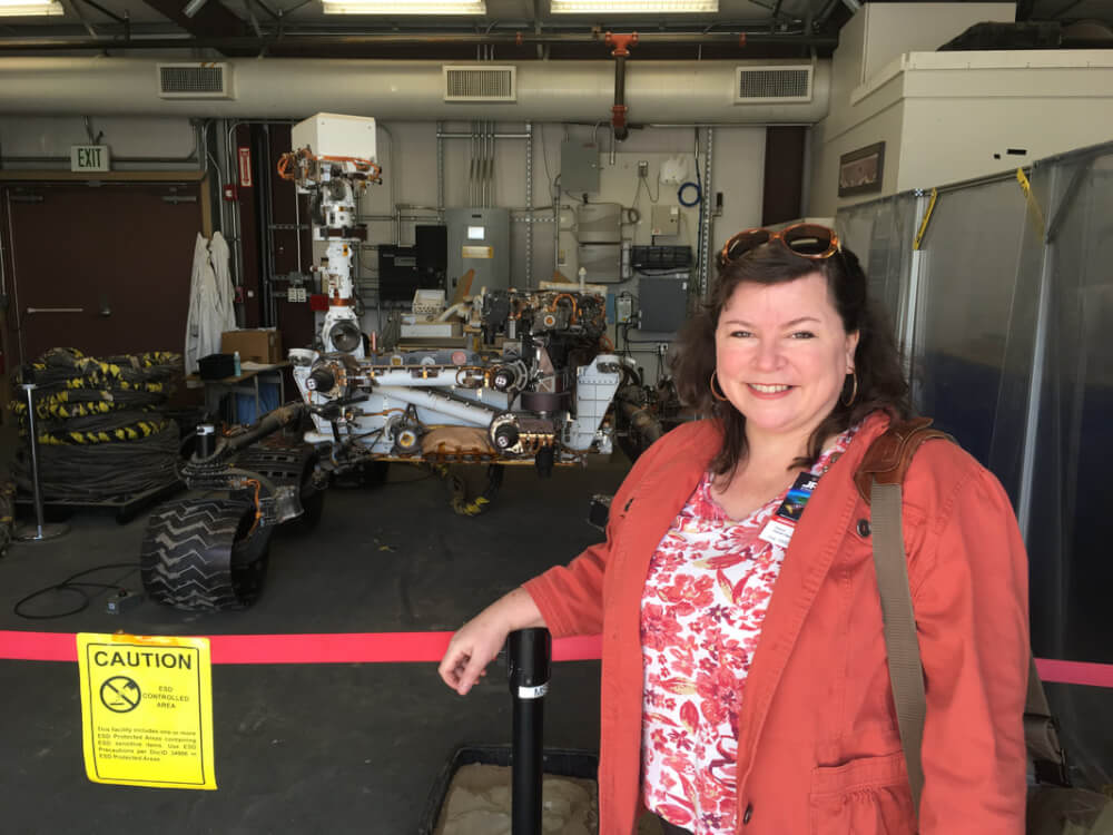 Deana Weibel stands with a copy of the Mars Curiosity rover, used for testing.