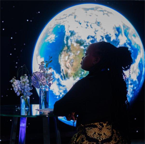 A visitor to GVSU's "The Blue Dot Experience," event is silhouetted against an image of the Earth.