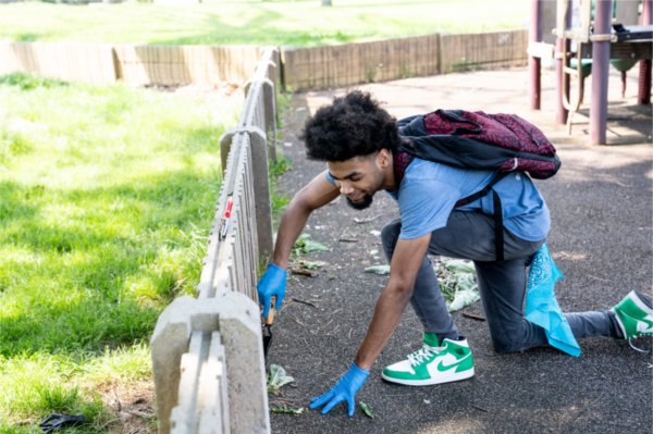 A student from University Prep Science and Math High School in Detroit pulls weeds from a playground at Belle Isle Park.