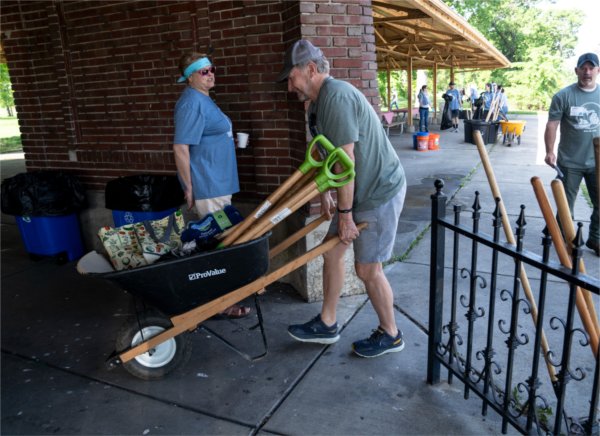 Dan Sippel, executive director with the West Michigan Tourist Association, hauls a wheelbarrow filled with tools for Michigan Cares for Tourism's cleanup project on Belle Isle Park. 