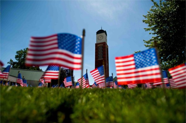  Small American flags frame a carillon tower on a college campus. 