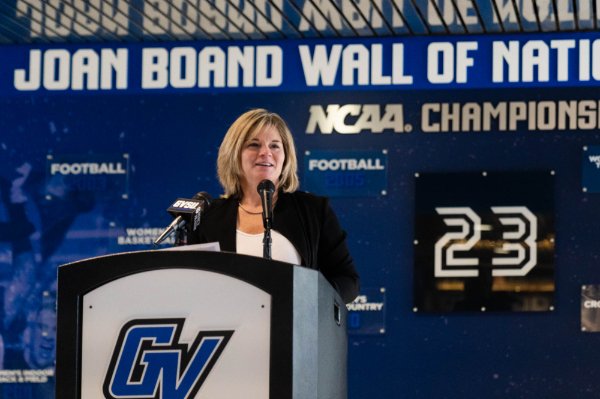 Keri Becker speaks at podium in front of wall reads: Joan Boand Wall of National Champions