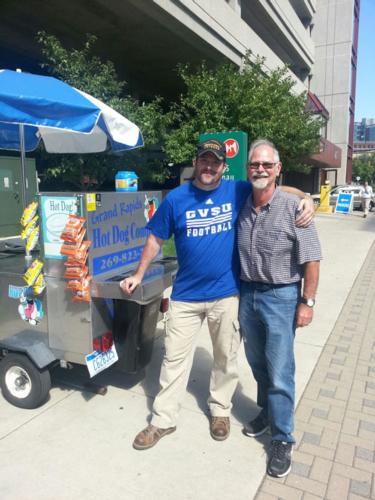 Student Steve Brown, left, stands by his hot dog cart. Proceeds from his ArtPrize sales will benefit the WGVU LZ Veteran Scholarship. 