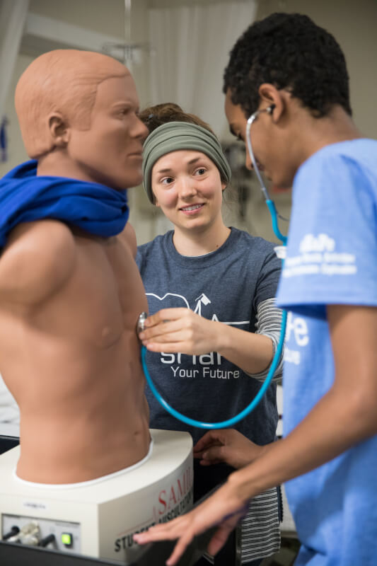 A Grand Valley nursing student helps campers analyze lung sounds during a nursing workshop.