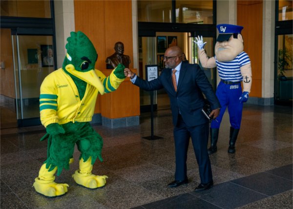 VP Truss gives a fist bump to a mascot, Louie the Laker in the background
