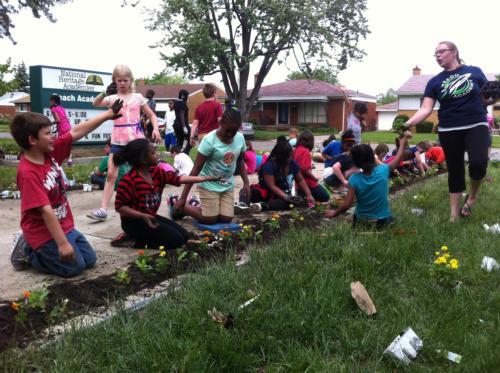 Alissa Dayringer, a teacher at Reach Charter Academy, helps students add landscaping around the school.