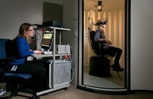 Photos by Rex Larsen<br>Mallory Lytikainen sits in a rotational chair in the Communication Sciences and Disorders neurophysiology lab. Goggles are used to track eye movements. At the workstation is faculty member Kara Hotaling.