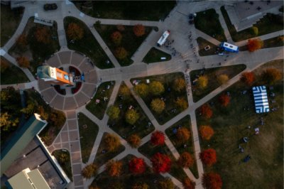 A carillon tower and zigzag patterns of sidewalks of a college campus are seen from a drone.