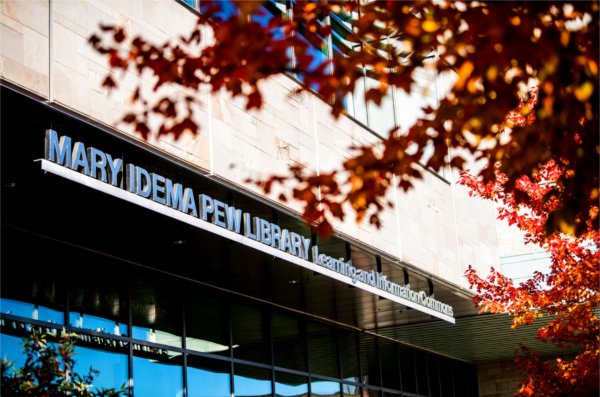  Red maple leaves frame the sign for the Mary Idema Pew Library learning and information commons.  