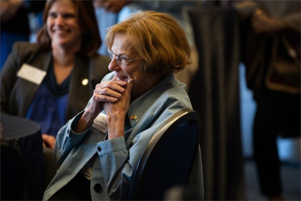  A woman holds her face in her hands while listening to remarks during an event. 