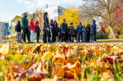 student leading tour near Zumberge Hall, ground covered in fall leaves