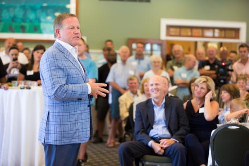 Notre Dame head football coach Brian Kelly gives remarks at a retirement reception for athletic director Tim Selgo, seated.