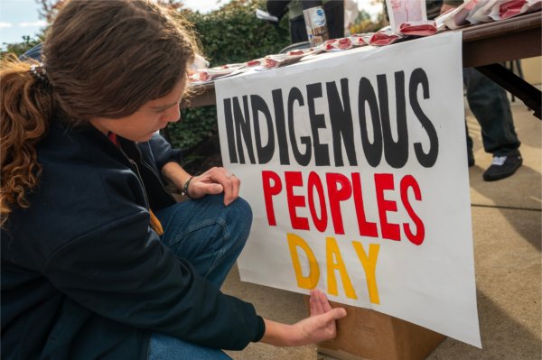 Simon Baker puts up signs as part of the Missing and Murdered Indigenous Persons (MMIP)'s Red Sand Project during Indigenous Peoples' Day. The project encouraged participants to pour red sand into sidewalk cracks to raise awareness for missing and murdered Indigenous women who fall through the cracks of society. 