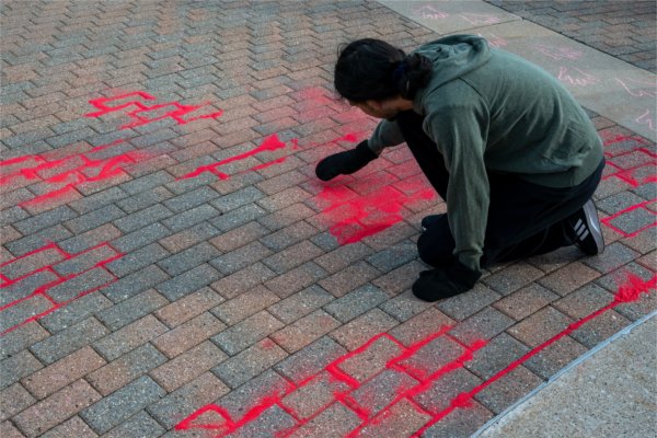 History major Anhel Coronado spreads red sand into sidewalk cracks as part of the Missing and Murdered Indigenous Persons (MMIP)'s Red Sand Project at the Cook Carillon Tower in Allendale during Indigenous Peoples' Day on Oct. 14. The project encouraged the GVSU community to pour red sand into sidewalk cracks to raise awareness for missing and murdered Indigenous women who fall through the cracks of society. Coronado is the president of the Native American Student Association (NASA).