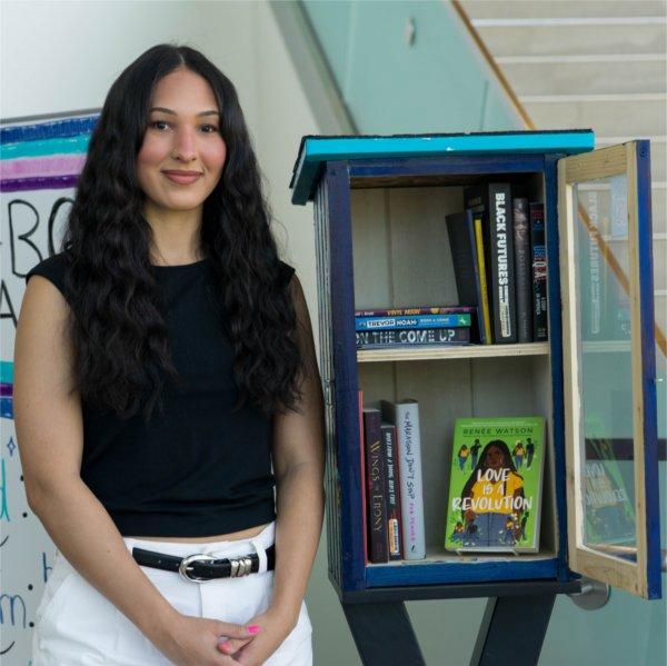 Jordyn Horton stands next to the Black Book Exchange Box in the Mary Idema Pew Library