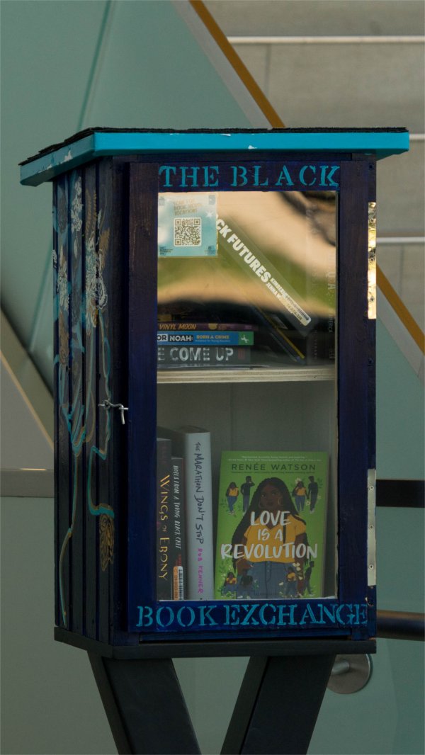 blue book box next to a staircase, The Black Book Exchange painted in light blue letters