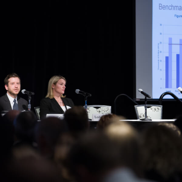 2 people at table, powerpoint slide in background
