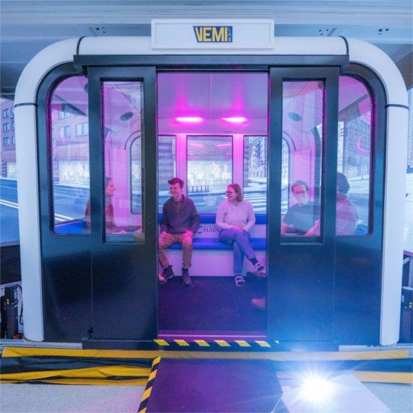 people seated in a multi-person autonomous vehicle simulator