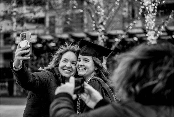  A mother and her daughter wearing a cap and gown take a selfie together. 