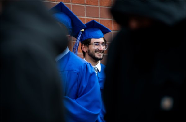  A graduate smiles while waiting in line with others. 