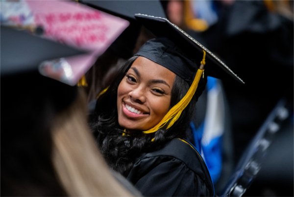 A graduate smiles at the camera.  