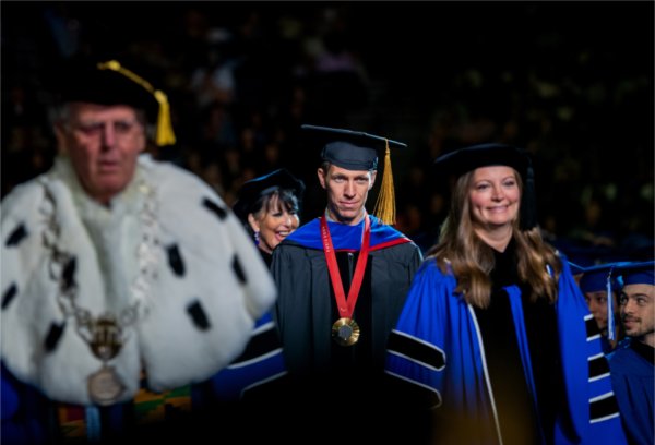  A group wearing academic regalia process in to a ceremony. 