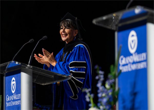  A university president in academic regalia speaks at the lectern. 