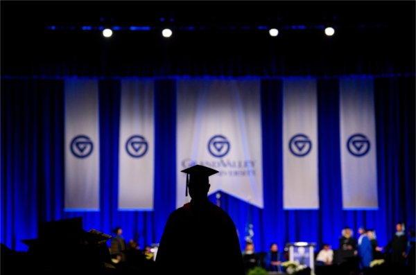  A graduate is silhouetted against the commencement stage. 