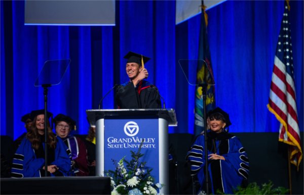  A guest speaker in regalia addresses a commencement crowd at the lectern. 