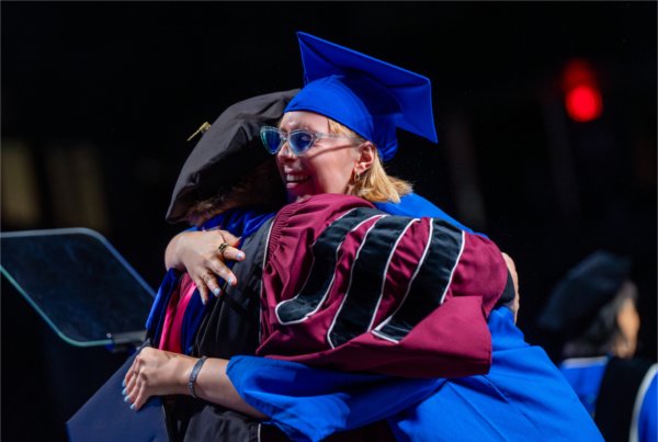  A graduate hugs a dean on stage. 